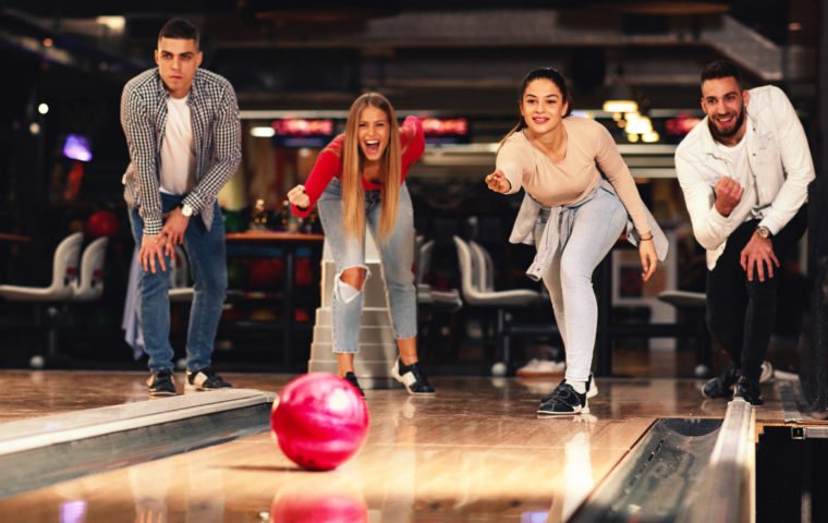 group of friends bowling and watching the ball roll down the lane