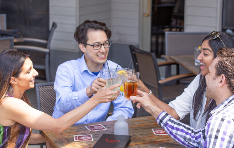 Four friends making a toast on the patio of The Loop