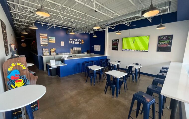 Interior of the brewery showing the bar counter and seating area, with a flat screen TV on the wall