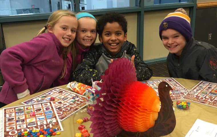 A group of kids sitting at a table playing bingo at the SLP Rec Center with a cute turkey centerpiece in front of them