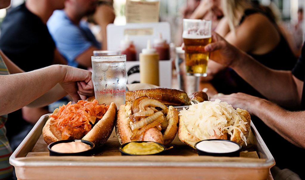 patrons enjoying hot dogs and beer at a table together