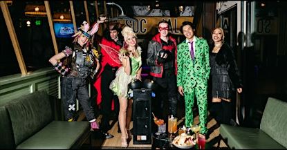 A group of adults dressed in Halloween costumes while bowling at Punch Bowl Social's Halloween Bash.