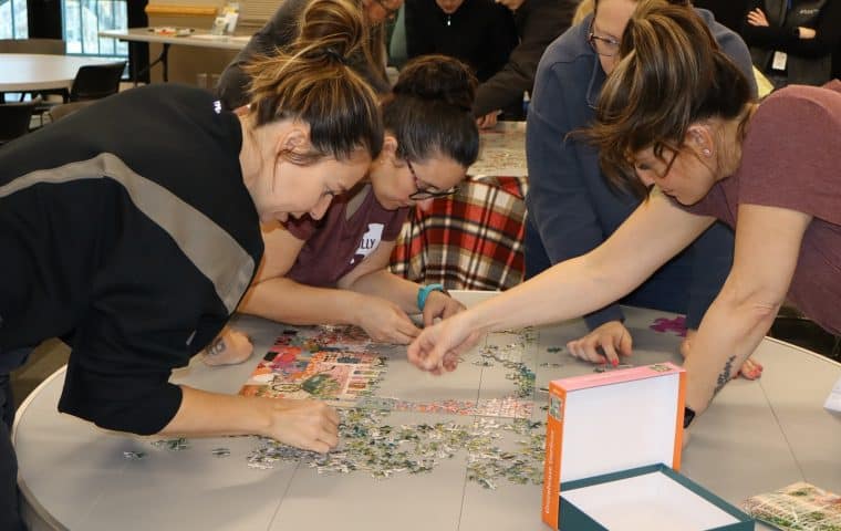 A team of 4 people race to complete a jigsaw puzzle in the shortest amount of time at Puzzlepalooza