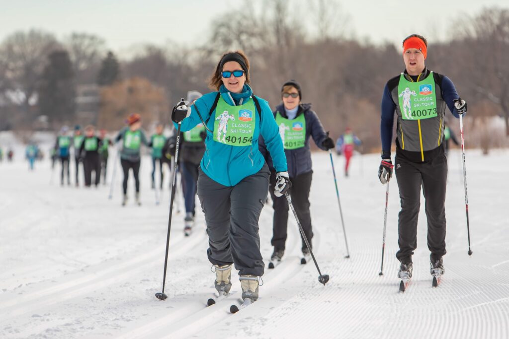 People cross-country skiing wearing loppet race bibs