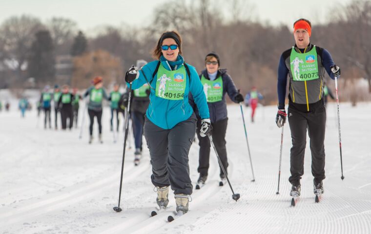 People cross-country skiing wearing loppet race bibs