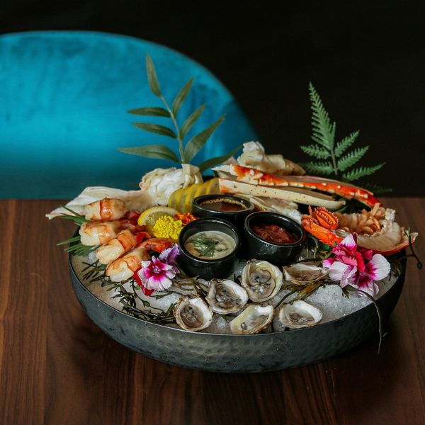 A bowl of ice filled with seafood, including oysters, shrimp and crab legs