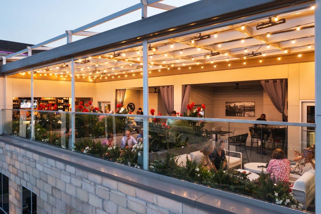 A drone photo showing REVEAL rooftop bar and it's new roof, with the roof lit up with twinkling lights as evening approaches
