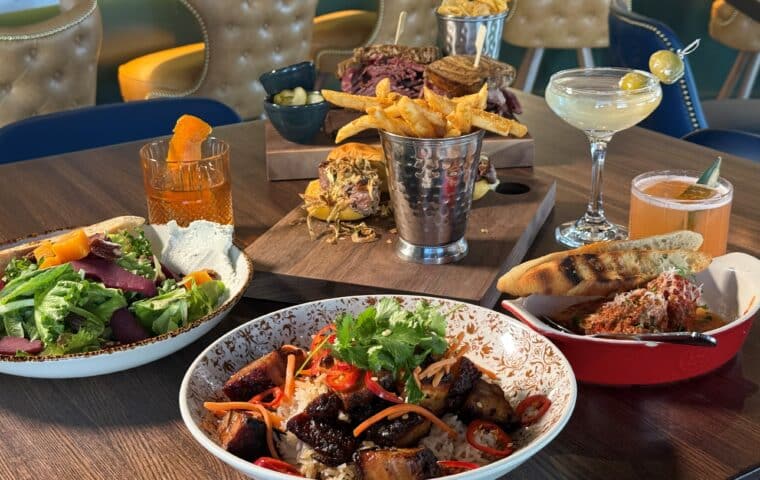 An array of dishes, including a harvest pear salad, Vietnamese pork belly, the Mort pastrami sandwich, filet mignon sandwich and three classic cocktails served at Kitchen and Rail in Golden Valley