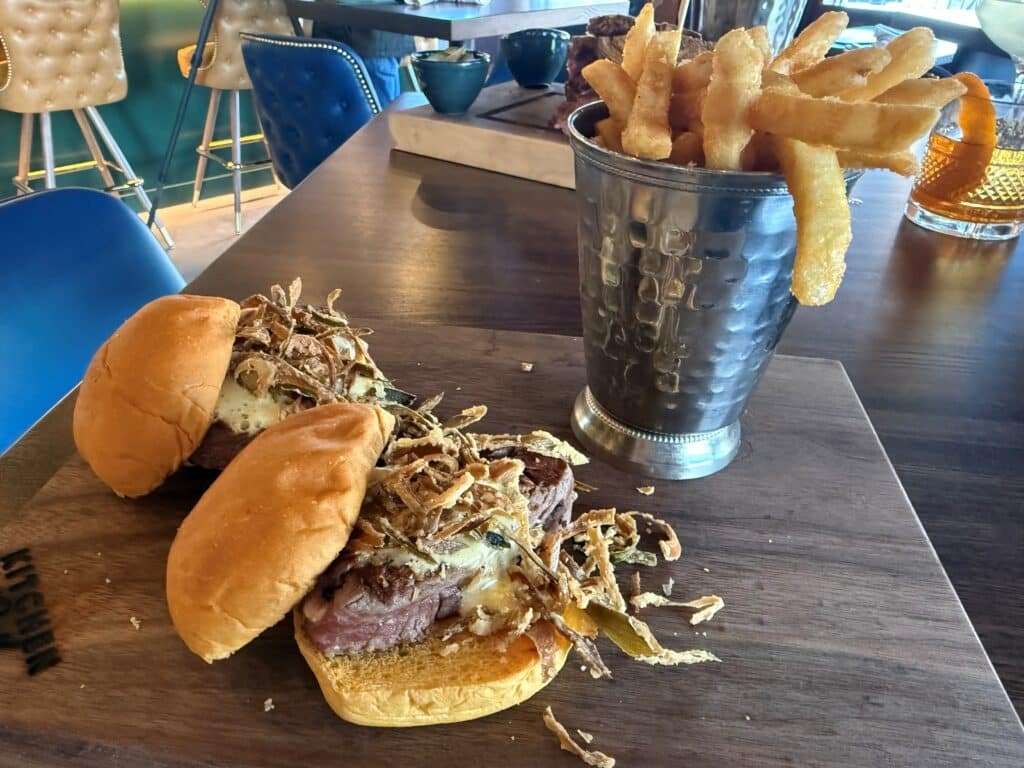 Two filet mignon sandwiches topped with frazzled onions and served with French fries at Kitchen and Rail in Golden Valley