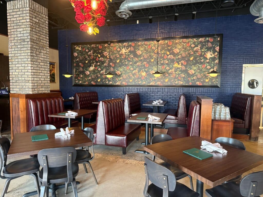 The main dining area featuring tables and booths and a floral backdrop at Kitchen and Rail in Golden Valley