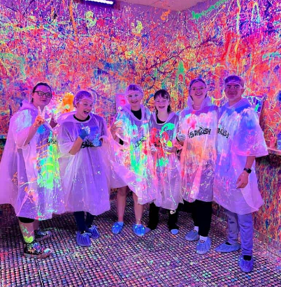 A group of kids wearing ponchos covered with paint after doing splatter art at iSMASH in St. Louis Park